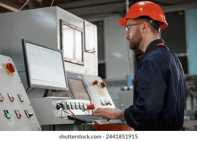 Operating the machine. Factory worker is indoors with hard hat. - Powered by Shutterstock