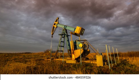 Operating Oil And Gas Well, In Remote Field, Under Warm Evening Light