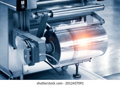 The operation of automatic plastic bag production machine with lighting effect. Close-up of the roller of the plastic bag production machine in the light blue scene with laser marking. 
