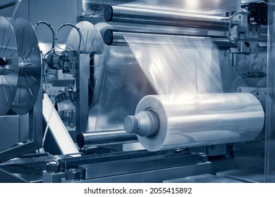 The operation of automatic plastic bag production machine with lighting effect. Close-up of the roller of the plastic bag production machine in the light blue scene.