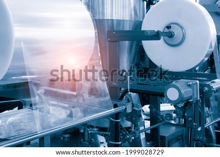 The operation of automatic plastic bag production machine with lighting effect. Close-up of the roller of the plastic bag production machine in the light blue scene. product packaging concept