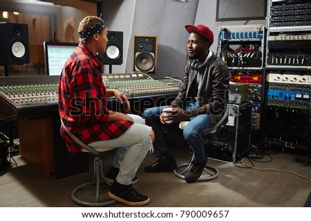 Operator of audio studio having talk with young musician about releasing new album