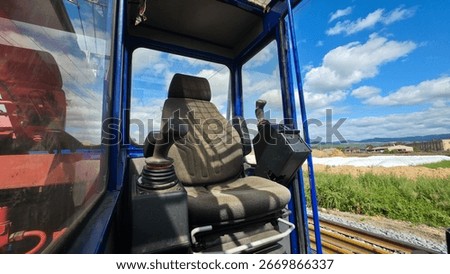 Operator cabin with empty seat and control levers inside industrial machine, symbol of work, engineering, and human interaction with technology.