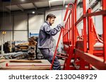 An operator climbing on machine and checking on it in heavy industry factory.