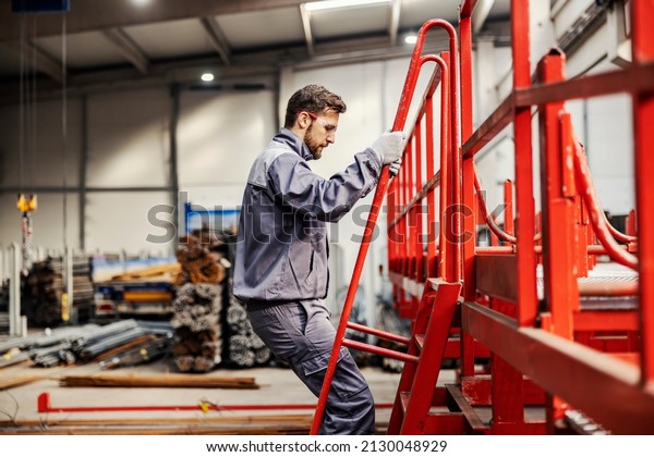 An operator climbing on machine and checking on\
it in heavy industry\
factory.