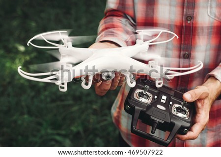 Operator holding remote control and quadrocopter. Unmanned aerial copter starting in forest. Aeromodelling, hobby, leisure concept