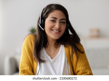 Operator of hot line. Portrait of friendly arab customer service representative wearing headset in call center, looking at camera and smiling. Support, contact us
