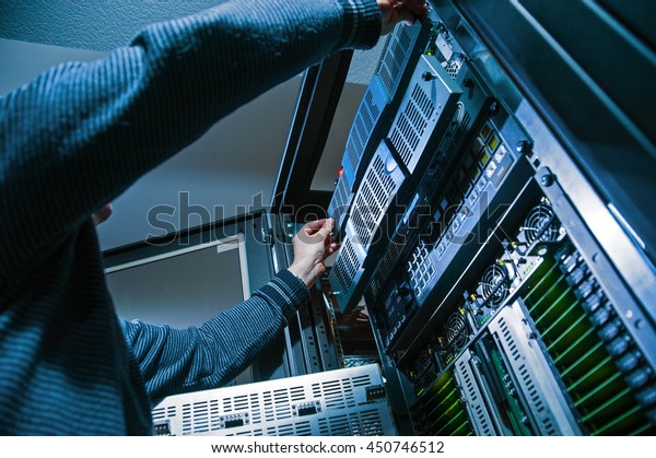 Operator Master repairs computer servers in a\
server room, close-up
