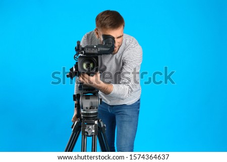 Operator with professional video camera on blue background