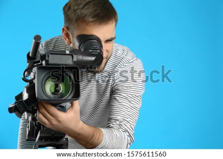 Operator with professional video camera on blue background