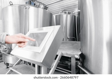 Operator uses computer to check quality and temperature of yeast fermentation in tanker hops and malt, beer production.