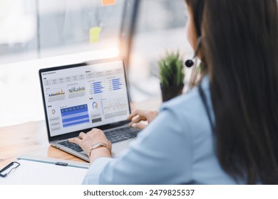 Operator wearing a headset, using a dashboard on laptop for data analysis in modern office - Powered by Shutterstock