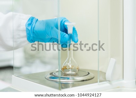 The operator is weighing the empty volumetric flask on the analytical balance for glassware calibration work, concept of qc laboratory in pharmaceutical industry.
