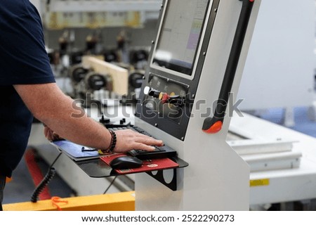Operator works at the control panel of the CAD CAM (computer-aided design and computer-aided manufacturing) woodworking machine. Selective focus.