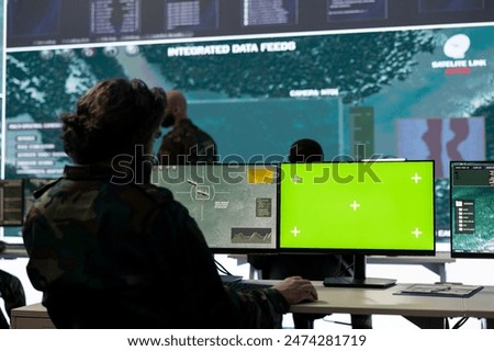 IT operator works with isolated display and tracking hostile vessels, transmitting gps location to the national guard power base. Military recruit operates on CCTV satellite system.