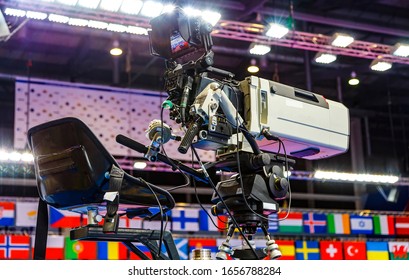operator's seat of a huge professional video camera for broadcasting sports events in 4K on background of flags championship participants