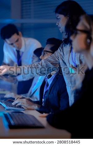 Operators wearing headsets work at computers in a dark modern call center monitoring data on glowing screens at night.