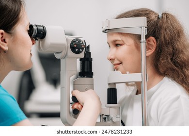 An ophthalmologist does an eye examination, working in a modern clinic with professional equipment. A girl checks a child's eyesight. - Powered by Shutterstock