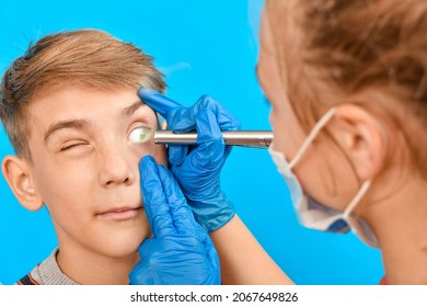 An ophthalmologist examines a teen's eye and shines a flashlight into his eye.