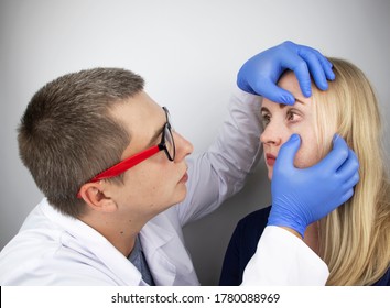 Eine Augenärztin untersucht eine Frau, die sich über ein brennendes Gefühl und Schmerzen in ihren Augen beschwert. Augenmüdigkeit durch einen Computerbildschirm oder ein Telefon (Sandgefühl auf der Hornhaut)