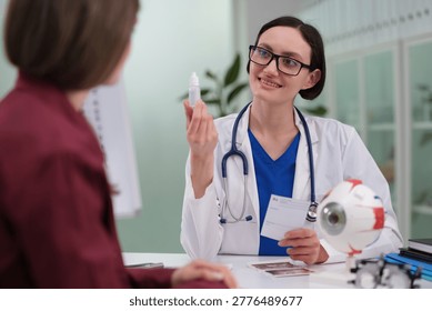 Ophthalmologist explaining eye drop usage and eye model, demonstrating instillation technique, vision care counseling