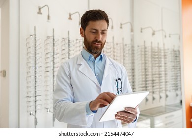 ophthalmologist with eyeglasses using digital tablet while working in optics store - Powered by Shutterstock