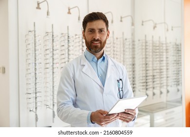 Augenarzt mit Brillen, die digitale Tablette verwenden, während sie im Optikgeschäft arbeiten