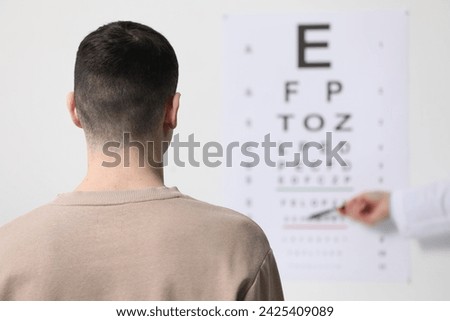 Ophthalmologist testing young man's vision in clinic, back view