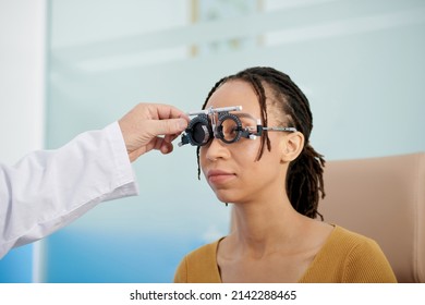 Ophthalmologist using adjustable optical trial lens frame to measure distance between eyes of patient