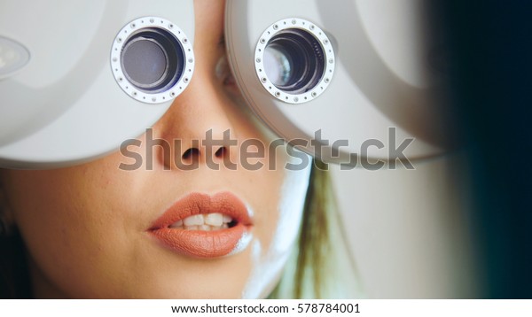 Ophthalmology clinic - woman checks vision by modern\
equipment - eyes exam, close\
up