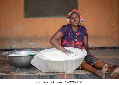 Opialu, Benue State - March 6, 2021: Smiling Middle Aged African Woman Working and Sitting on the Floor while Sieving Process Cassava Flour (Garri)