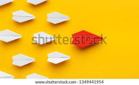 Opinion leadership. Red paper plane leading another colorful ones, influencing the crowd, yellow background, panorama