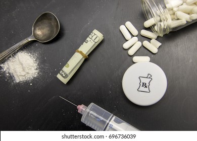 Opiods in pill, powder and syringe on chalkboard with rolled twenty dollar bills.