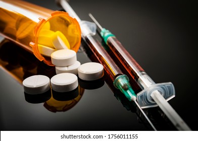 Opioid epidemic, drug abuse concept with closeup on two heroin syringes or other narcotics surrounded by scattered prescription opioids. Oxycodone is the generic name for a range of opioid painkillers