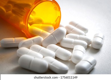 Opioid epidemic, painkillers and drug abuse concept with close up on a bottle of prescription drugs and hydrocodone pills falling out of it on white