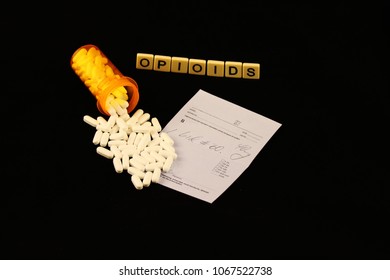 Opioids Spelled Out With Tiles Over Spilled White Prescription Pills Over A Prescription Pad On A Black Background
