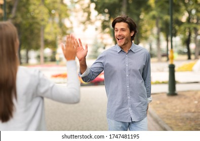 Opposite-Sex Friendship. Man Waving Hello Gesture Meeting Female Friend Walking Outdoors In Park. Selective Focus