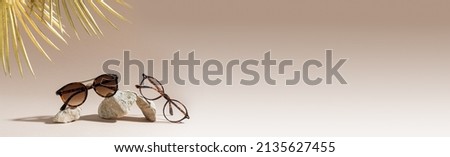 Optic store advertisement banner. Clear Eyeglasses Glasses with plastic Frame and trendy sunglasses on a beige Background. Tortoiseshell frame glasses on stones. Copy space. Optic store web line