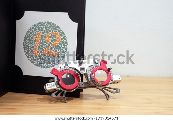 Optical equipment, optical trial\
lens frame on wooden table, and color blindness test\
chart