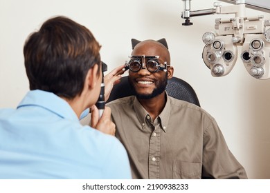 Optical Exam, Optician Or Eye Doctor At Work Testing Vision Or Sight Of Patient At Optometrist. Happy, Smiling Young Man Checking His Eyes For Glasses Or Treatment At An Ophthalmologist In A Clinic.