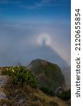 Optical illusion, brocken spectre, unique phenomenon in High Tatras on a hike, sunlight projecting tourist shadow on fog surrounded by rainbow halo glory on mountain ridge and rocky peaks