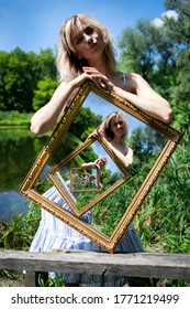 Optical illusion. The composition of an infinite image in a picture. A girl with blond hair on the lake shore holds a picture with an infinite image. A picture within a picture.