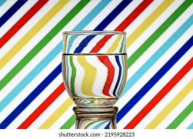 Optical illusion created by refracting light with a glass of water and colored diagonal lines