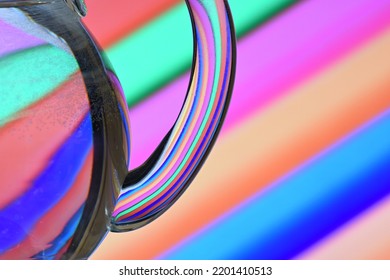 Optical Illusion Created By Refracting Light With A Glass Container Filled With Water And Colored Diagonal Lines