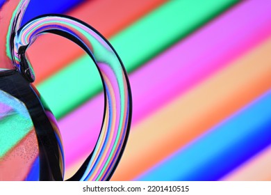 Optical Illusion Created By Refracting Light With A Glass Container Filled With Water And Colored Diagonal Lines