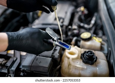 Optical instrument for testing antifreeze, windshield washer fluid and electrolyte density. Mechanic uses car refractometer in service - Shutterstock ID 2257053353