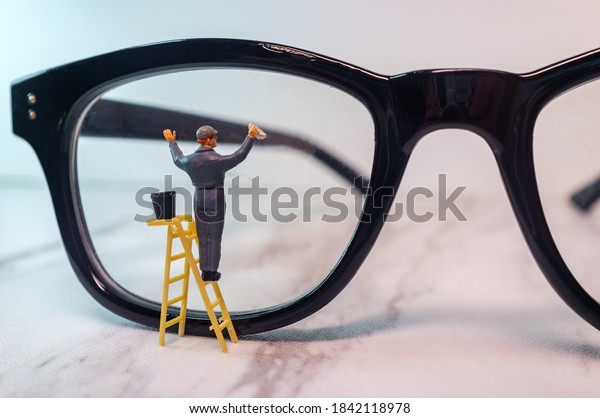 Optician eyeglasses being cleaned by tiny figurine\
symbolizing clear\
vision