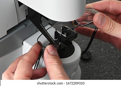 Optician hands adjusting eyeglasses during measurement of dioptry with modern digital lens meter. 