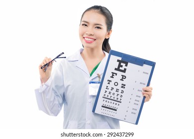 Optician Or Optometrist Pointing At Snellen Eye Exam Chart. Woman Eye Doctor Wearing Glasses On White Background. Female Caucasian / Asian Model. Healthcare, Advertisement And Medicine Concept.