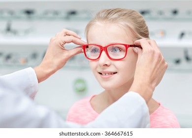 Optician Putting Glasses To Girl At Optics Store